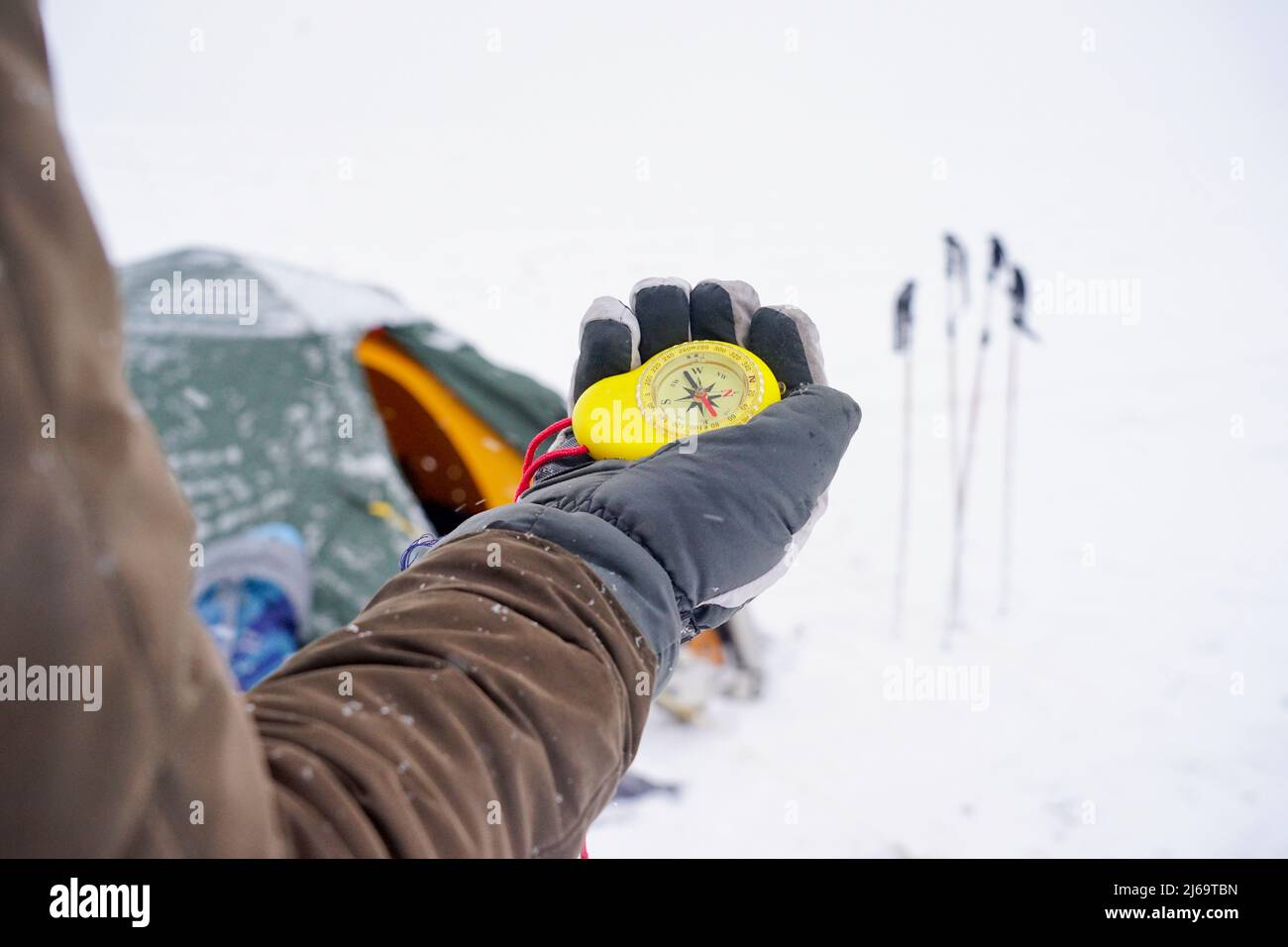 Big beautiful yellow compass in hand. A traveler holds a gloved compass at the north pole in winter. Compass on a winter expedition Stock Photo