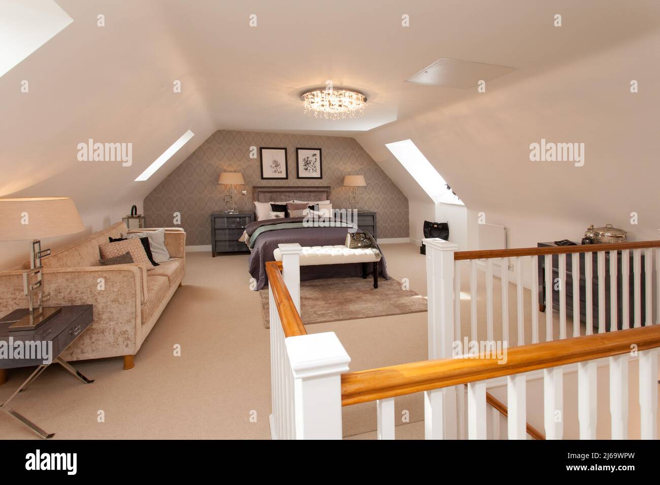 Loft conversion bedroom with sofa , bed and dormer windows to both sides, staircase and bannister rail Stock Photo