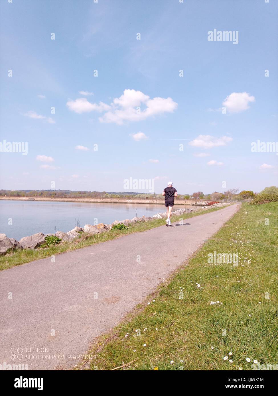 A man seen from behind running along the edge of the harbour Stock Photo