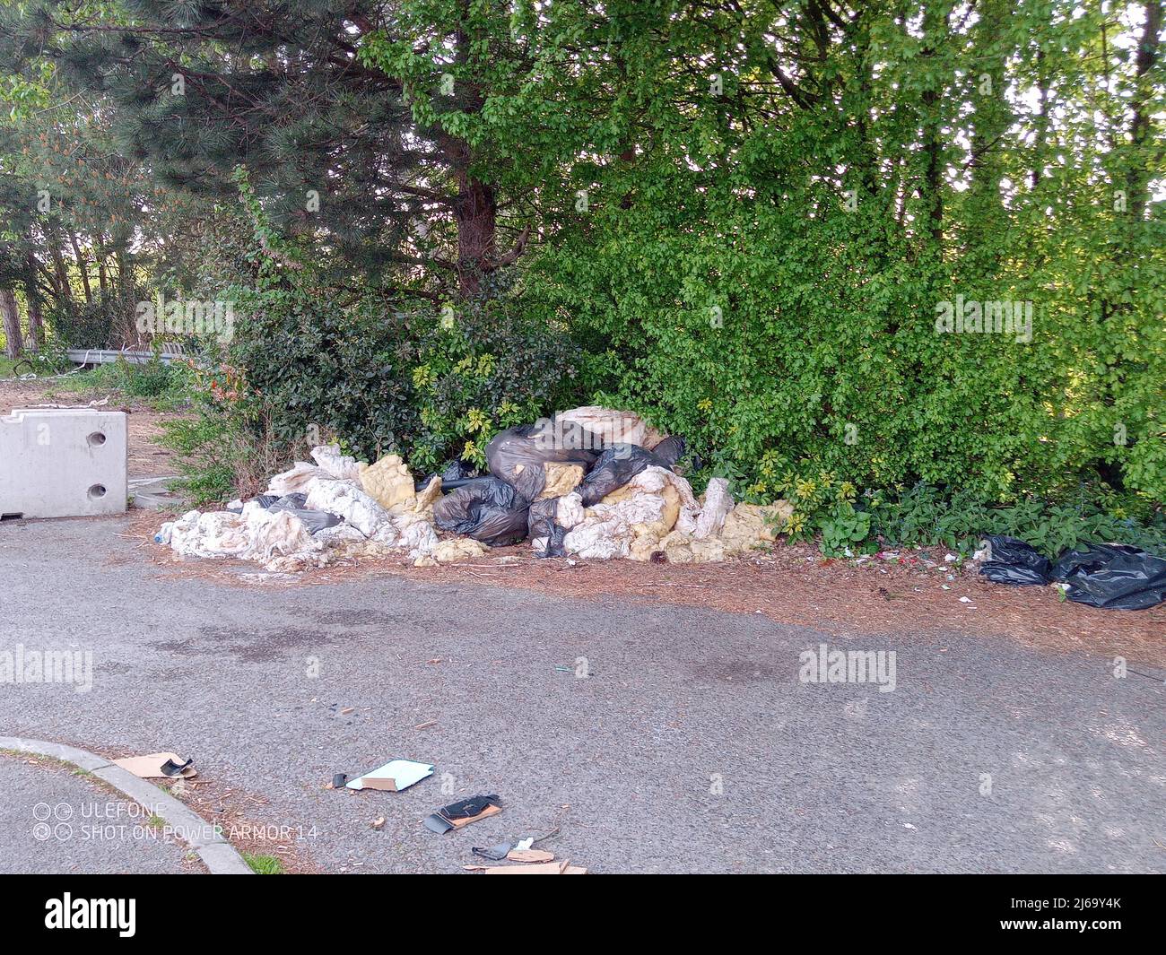 Close-up of dumped rubbish consisting of black plastic bags of used insulation material in a car park Stock Photo