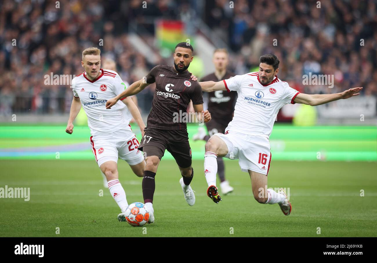 Germany. 29th Apr, 2022. 29 April 2022, Hamburg: Soccer: 2nd Bundesliga, Matchday 32, FC St. Pauli - 1. FC Nürnberg at Millerntor Stadium. St. Pauli's Daniel-Kofi Kyereh (center) battles for the ball with Nuremberg's Tim Handwerker (left) and Christopher Schindler. Photo: Christian Charisius/dpa - IMPORTANT NOTE: In accordance with the requirements of the DFL Deutsche Fußball Liga and the DFB Deutscher Fußball-Bund, it is prohibited to use or have used photographs taken in the stadium and/or of the match in the form of sequence pictures and/or video-like photo series. Credit: dpa picture allia Stock Photo