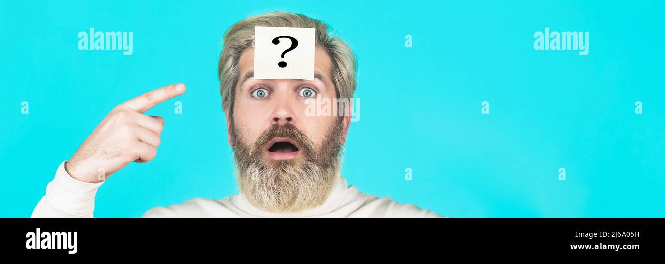 Paper notes with question marks. Thinking man with question mark on blue background. Man with question mark on forehead looking up Stock Photo