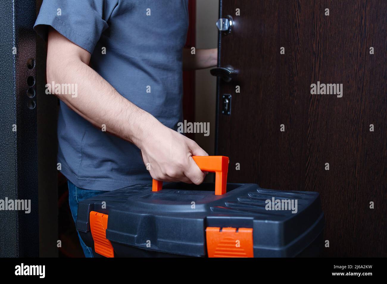 Man with a suitcase of tools coming in client home. Repairman or husband on hour service, hands holding a toolbox. Stock Photo