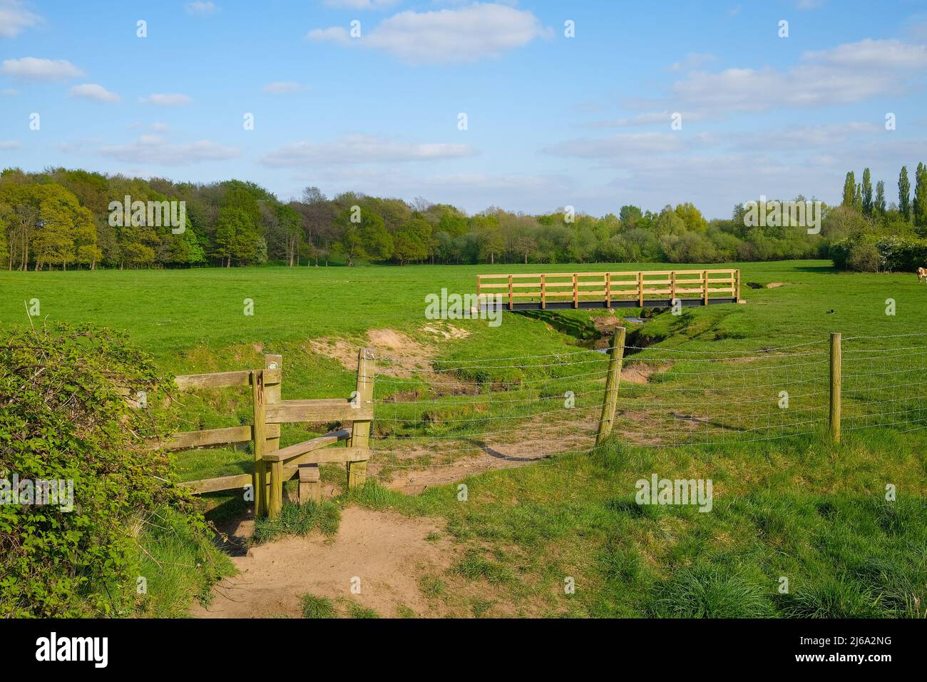 open farmland stream wooden stile and bridge next to Monton village Eccles Manchester UK Stock Photo