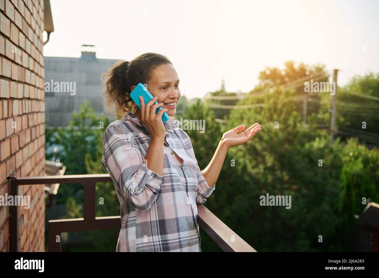 Beautiful Hispanic woman talking on mobile phone standing on the ...