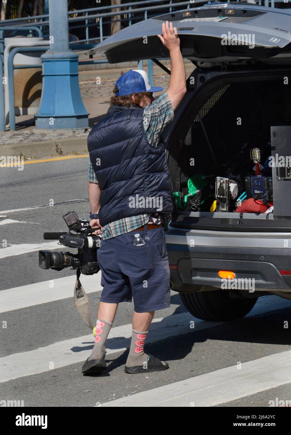 A television cameraman employed by KTVU-TV loads his Canon video camera in the trunk of his van after an assignment in San Francisco, California. Stock Photo
