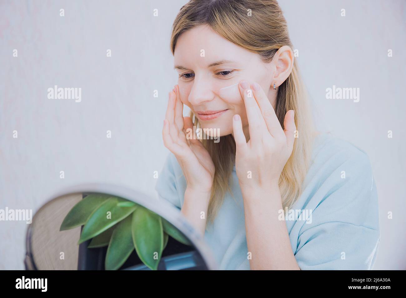 Portrait of an attractive young woman applying moisturizer to her face at home. Skincare, skin
