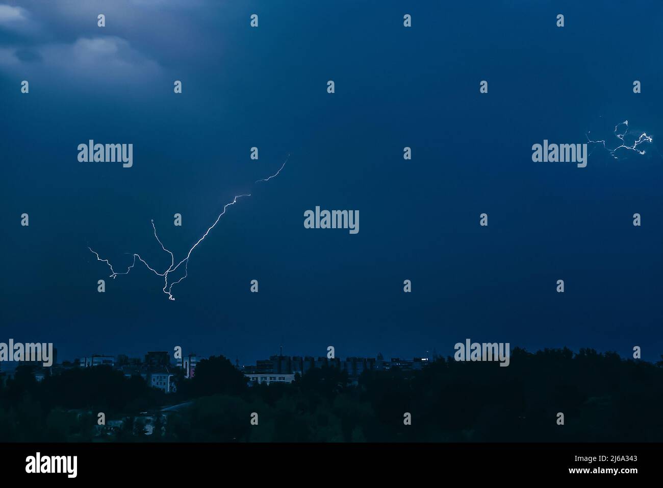Lightning in sky over city. Bright flashes on dark night. Thunderclouds ...