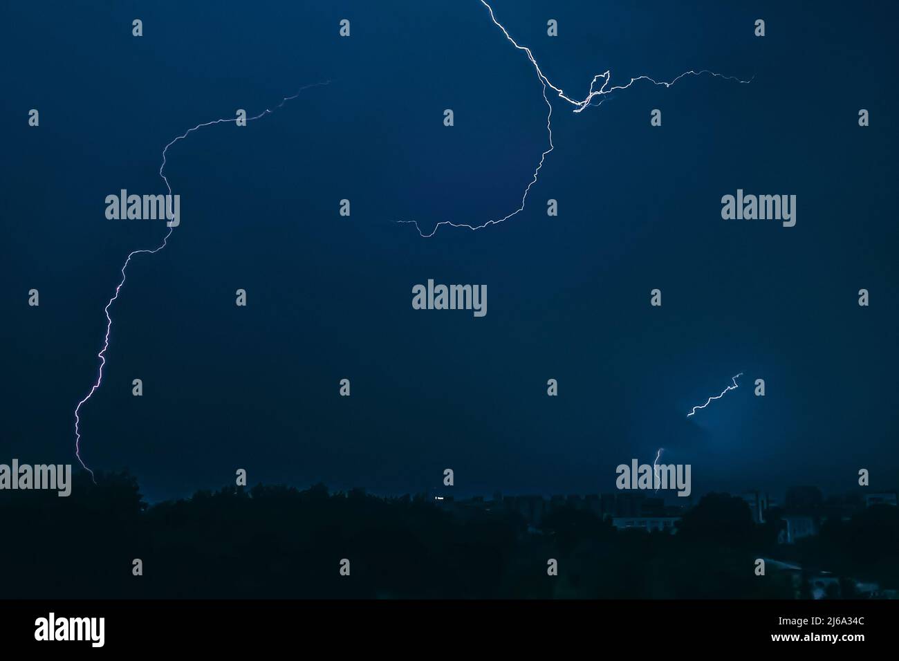 Lightning in sky over city. Bright flashes on dark night. Thunderclouds