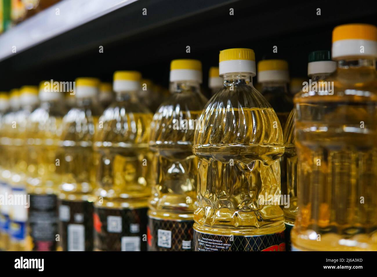 A lot of yellow sunflower oil bottles on the shelves in the supermarket