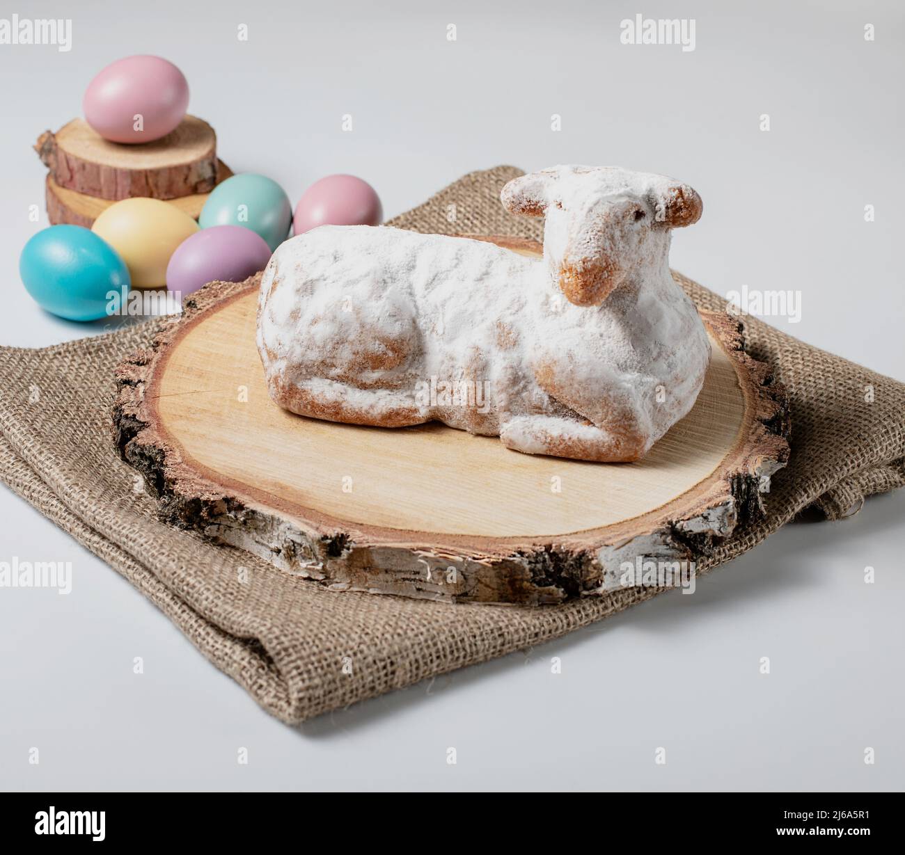 Traditional easter sweet lamb cake with powdered sugar, eggs, wood and sack on white background