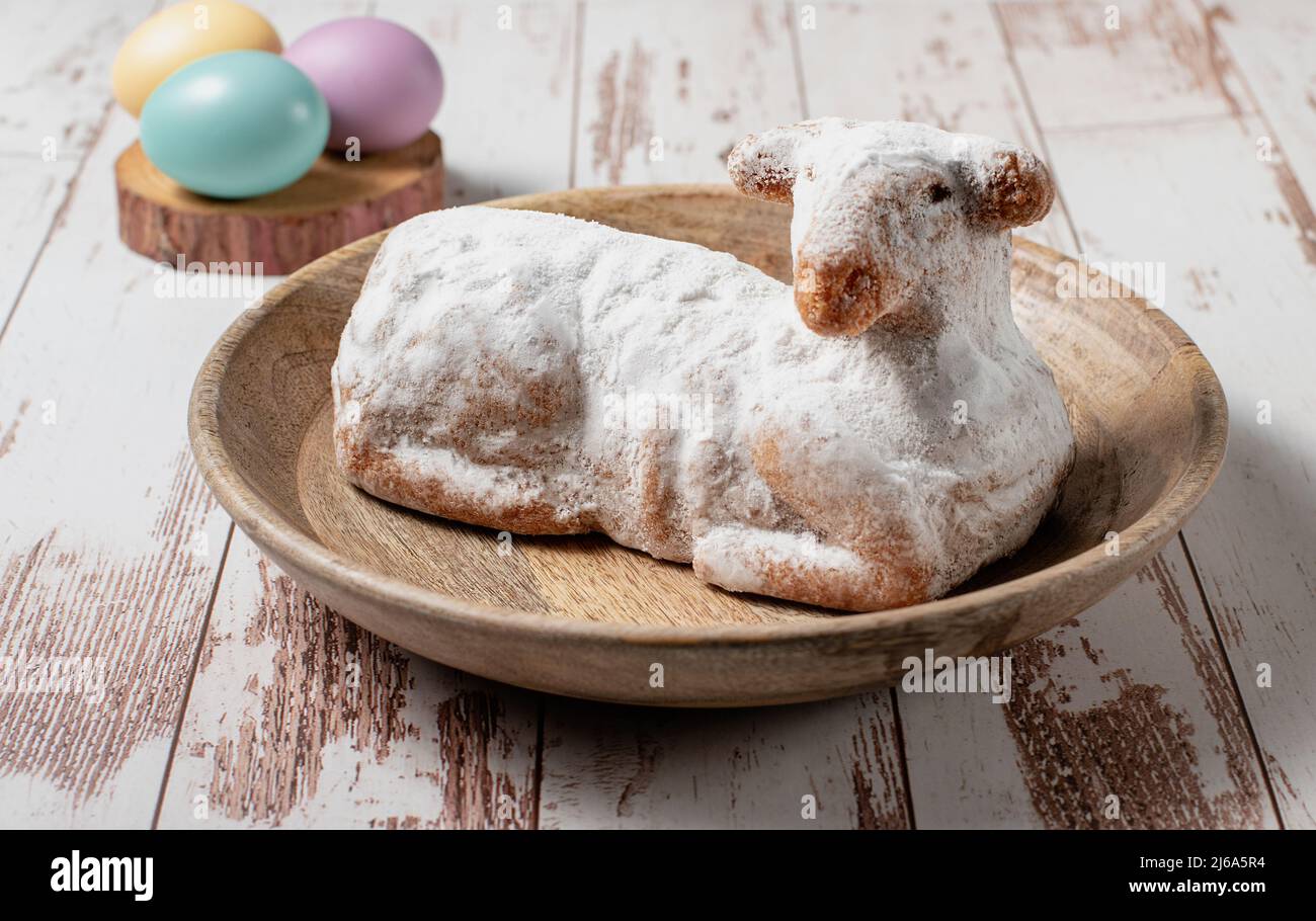 Traditional easter sweet lamb cake with powdered sugar and eggs served on a wooden plate, stock