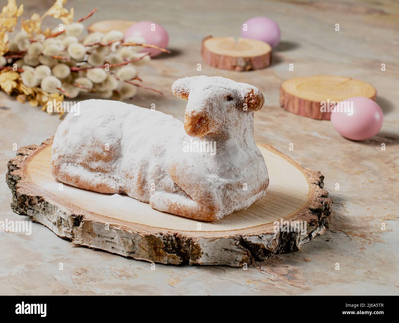 Traditional easter sweet lamb cake with powdered sugar, willow and eggs on wooden background