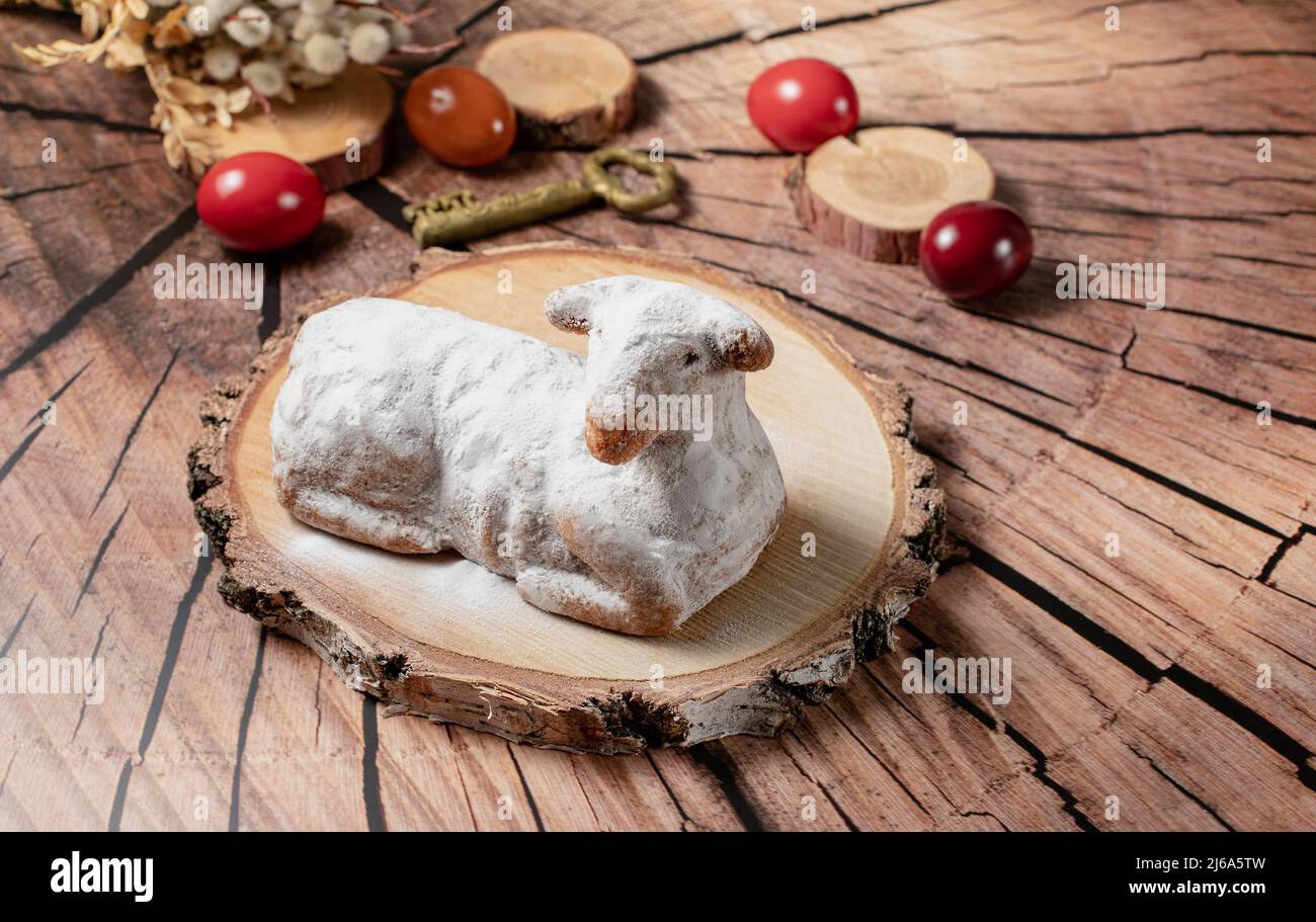 Traditional easter sweet lamb cake with powdered sugar, willow and eggs on wooden background