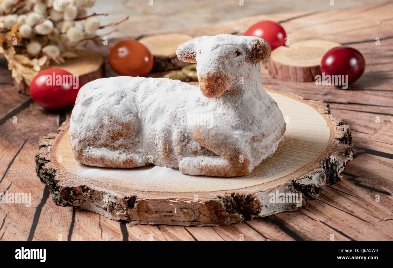 Traditional easter sweet lamb cake with powdered sugar, willow and eggs on wooden background