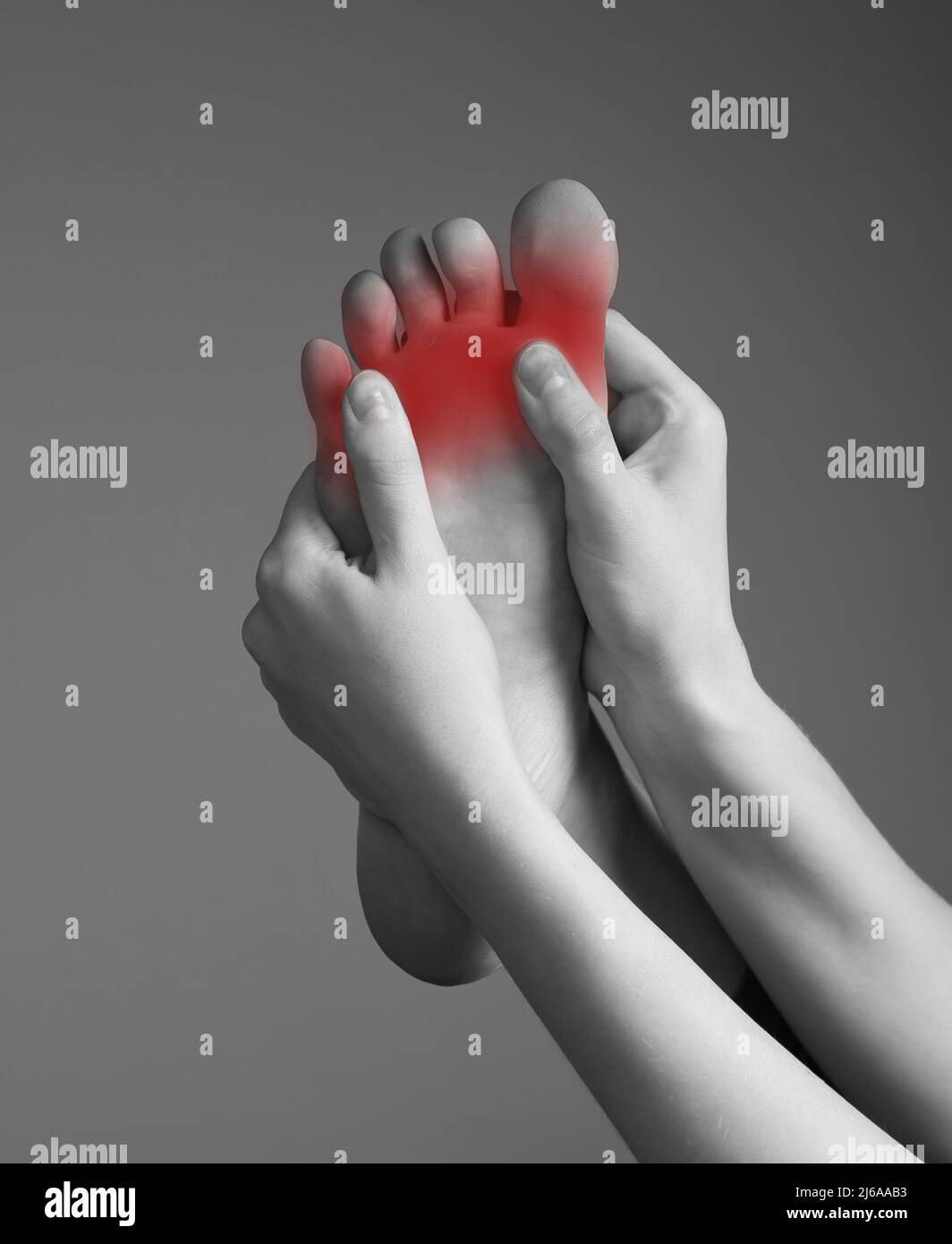Toe pain caused by overuse, injury, arthritis, bunion, calluses, tight shoes. Woman hands holding foot with red spot. Black and white. Orthopedic complaints and health problems concept. photo Stock Photo