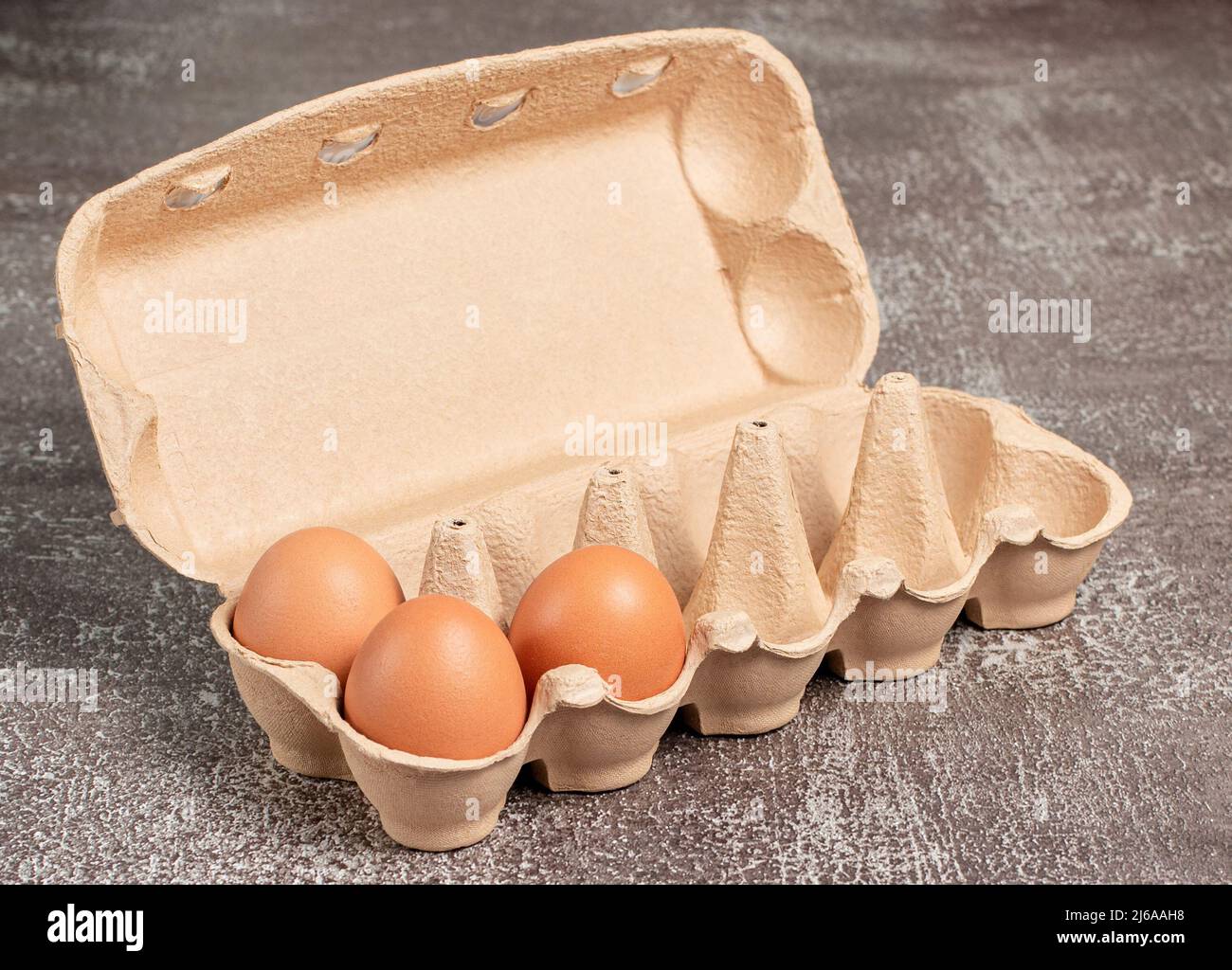 Fresh organic chicken eggs in open carton pack or egg container on brown background, set, stock photo Stock Photo