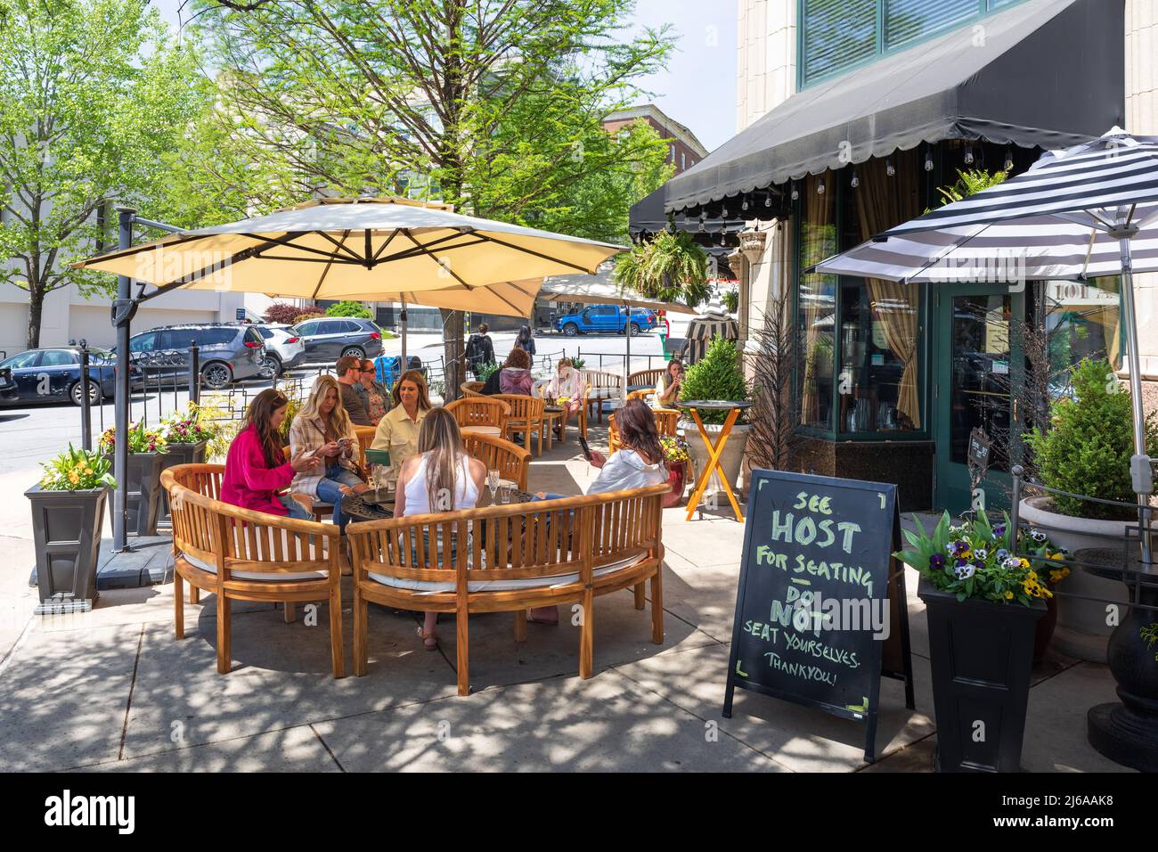 ASHEVILLE, NC, USA-28 APRIL 2022:Young women sitting under awning at The Book Exchange Champagne Bar, with entrance to bar on right. Stock Photo
