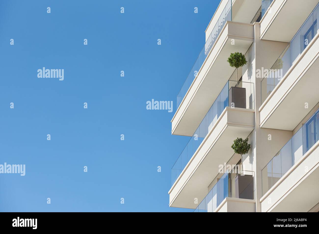 Balcony with glass railing in a modern apartment building against a blue sky with a copy space Stock Photo