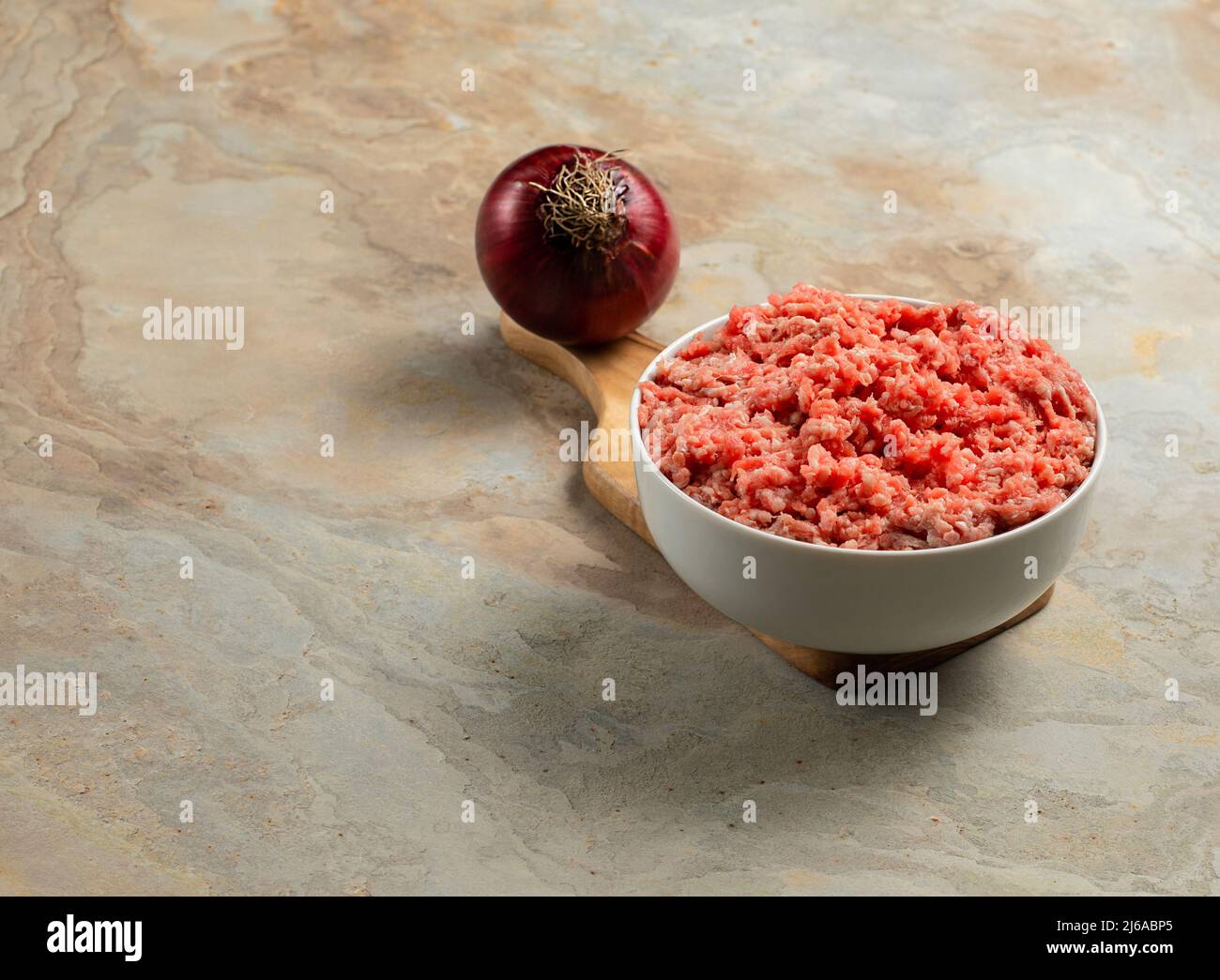 Plate with fresh ground beef, onion on a brown vintage background, space for text, stock photo Stock Photo