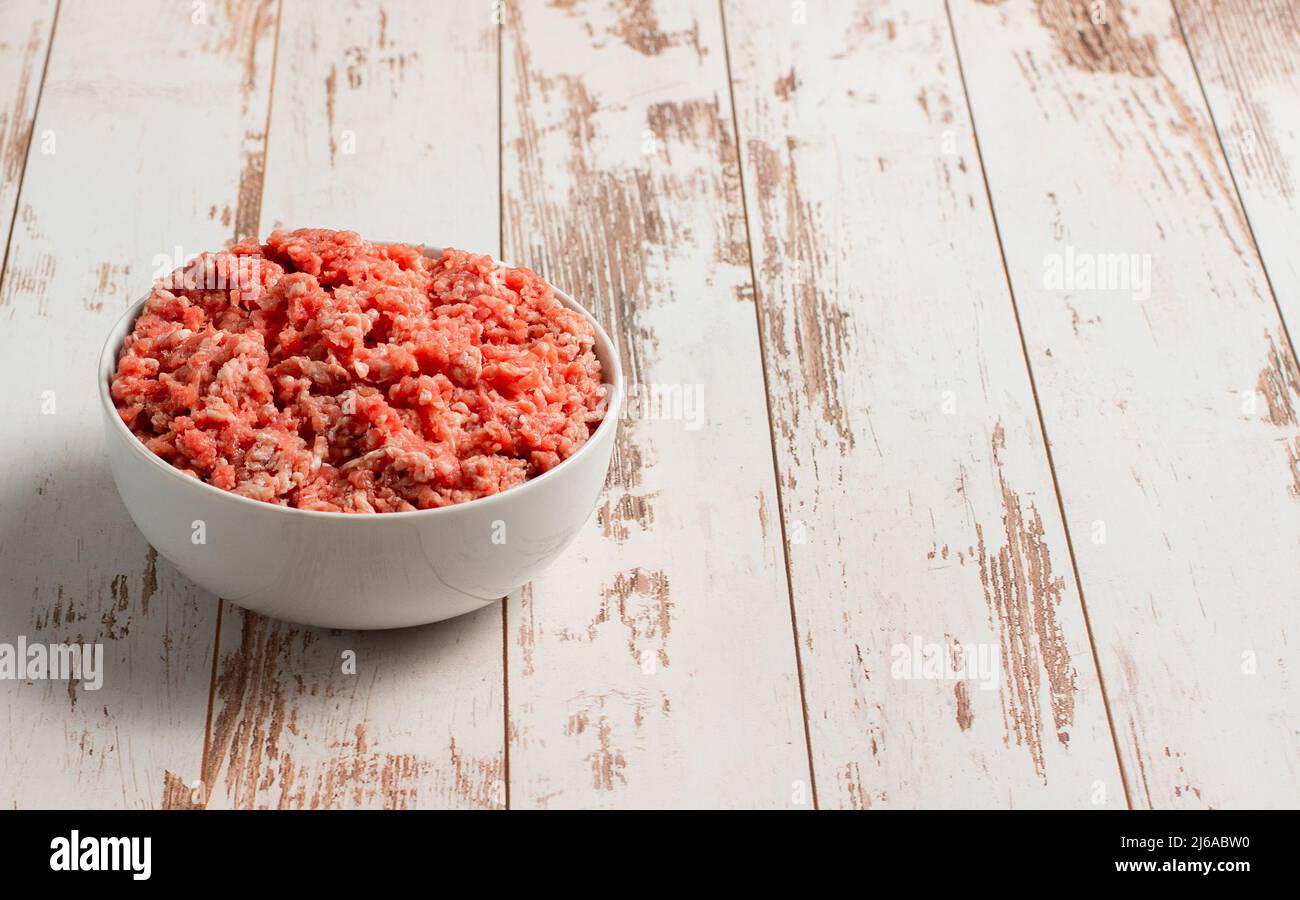 Plate with fresh ground beef on a brown wooden background, space for text, stock photo Stock Photo