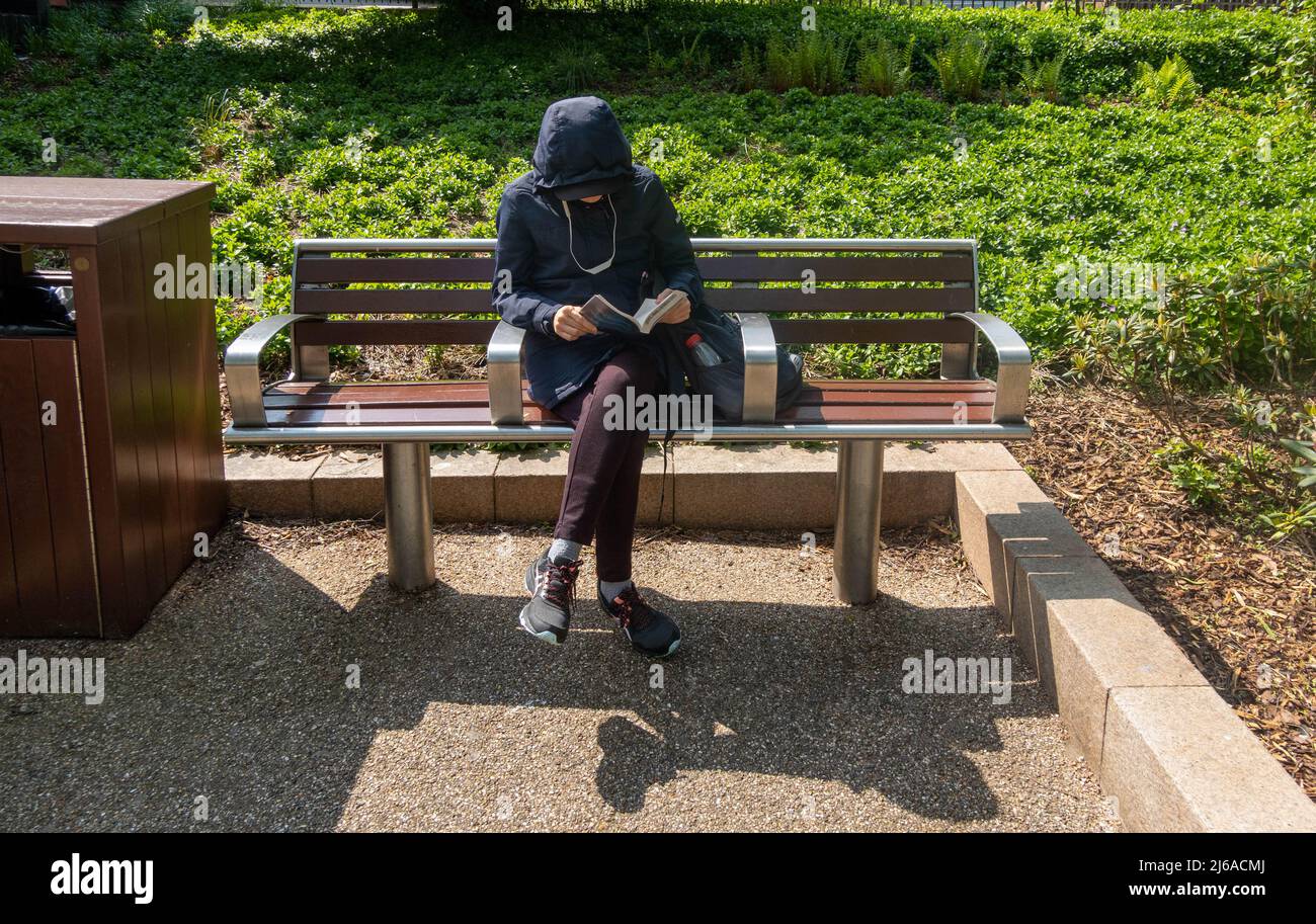 Woman sitting on a park bench reading a paperback book Stock Photo - Alamy
