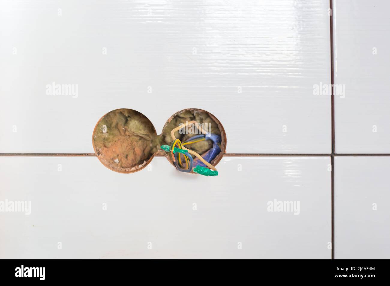 Holes in the tiles on the wall for an electrical double socket