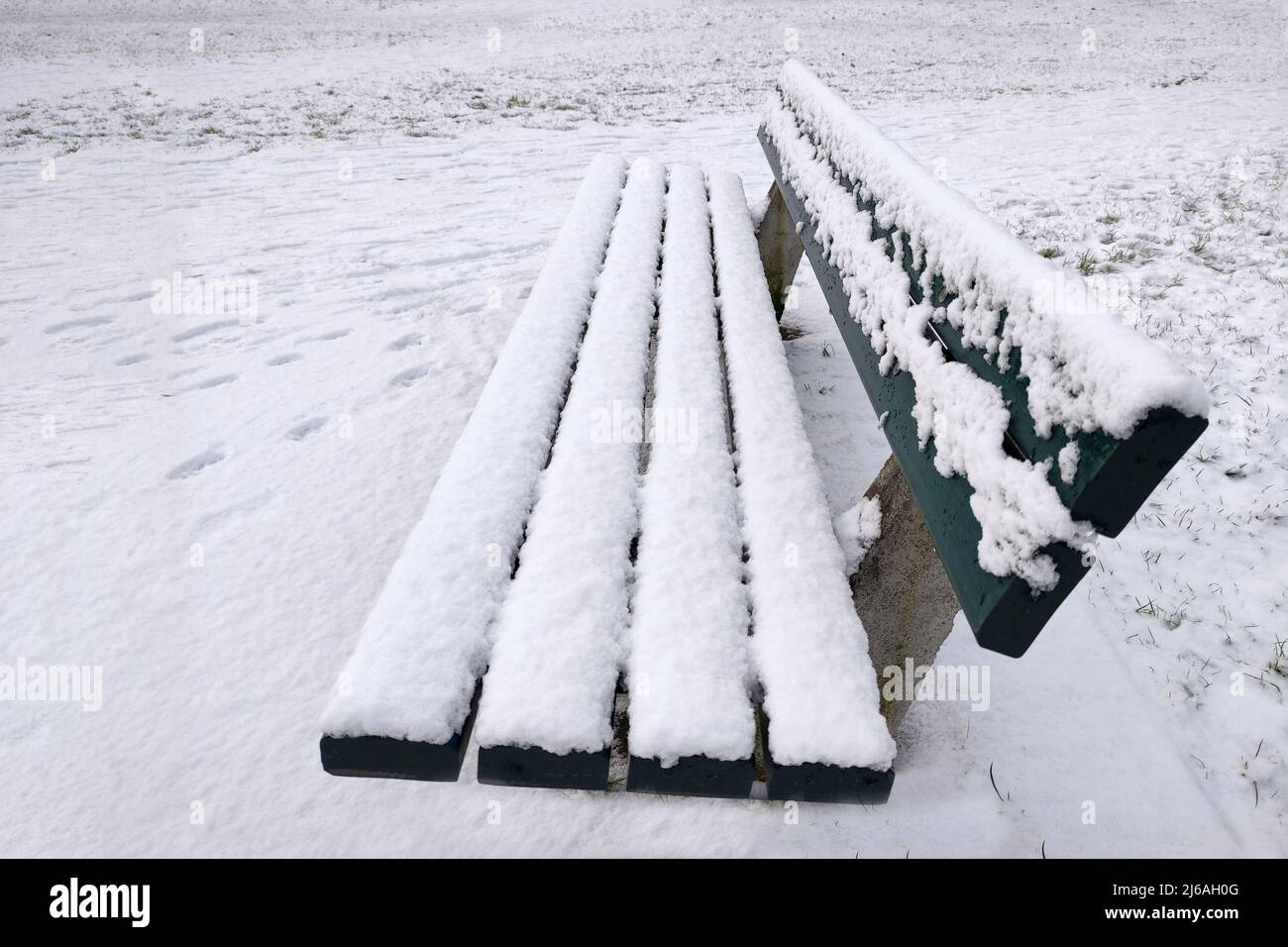 Park bench in the snow, fresh snow during thaw. Stock Photo