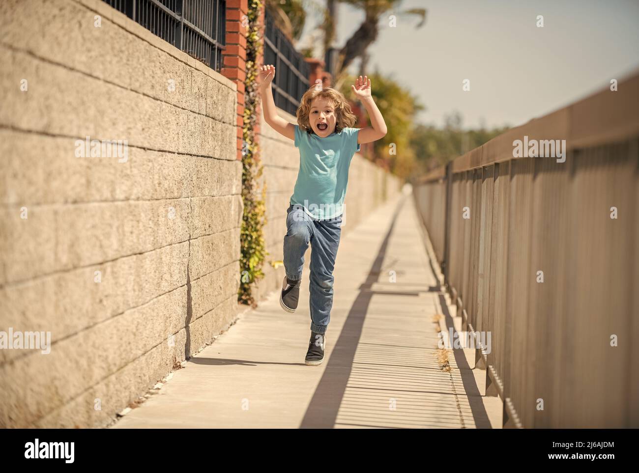 Excited energetic boy child scream running on summer promenade, excitement Stock Photo