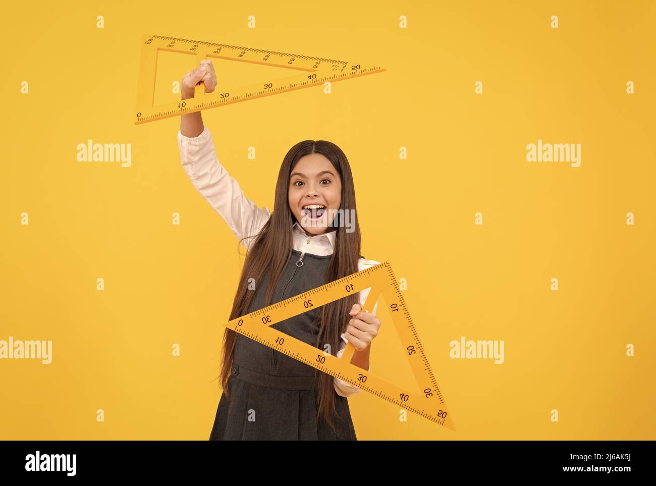 happy kid hold math triangle ruler in school on yellow background ...