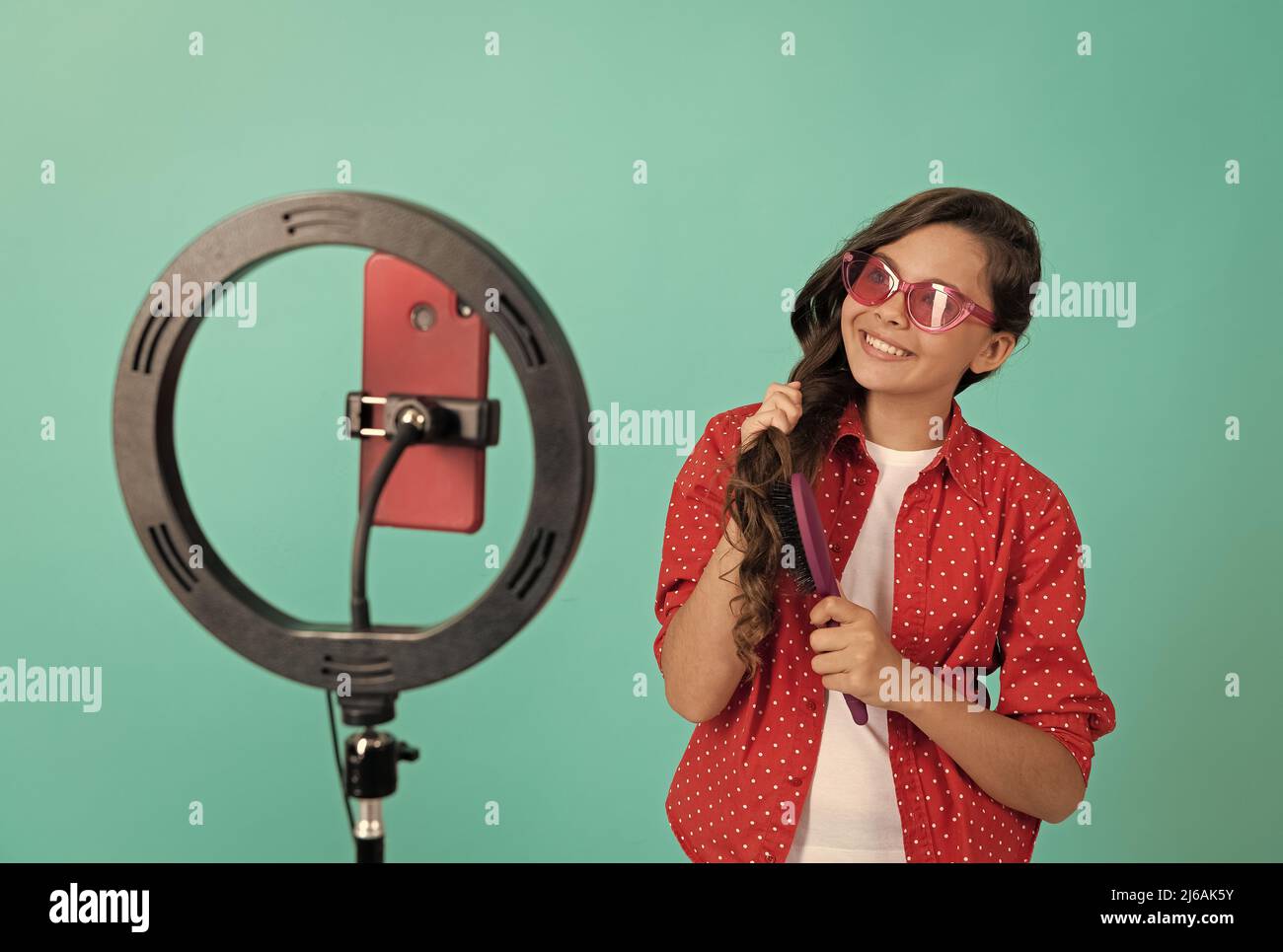 happy teen girl brushing with comb blogging online, beauty. Stock Photo