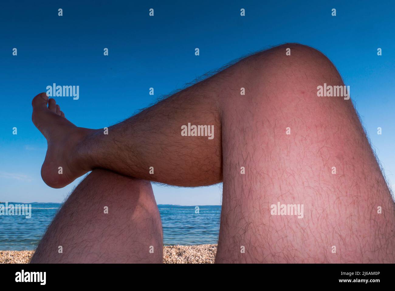 Man's legs are sunbathing on a beach. Point of view. Stock Photo