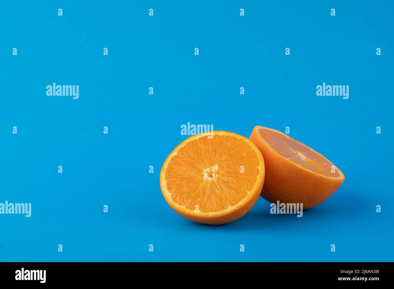 Two navel orange halves on solid blue background Stock Photo Alamy
