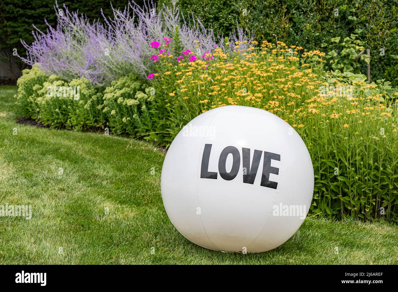Large white inflatable ball with LOVE printed on it within a colorful background Stock Photo