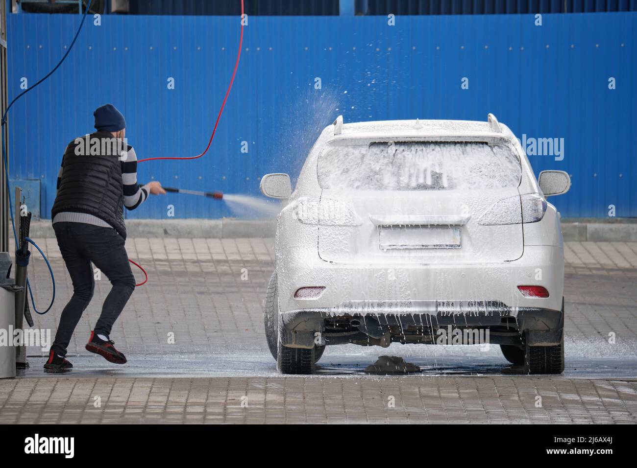 Closeup of male driver washing his car with contactless high pressure