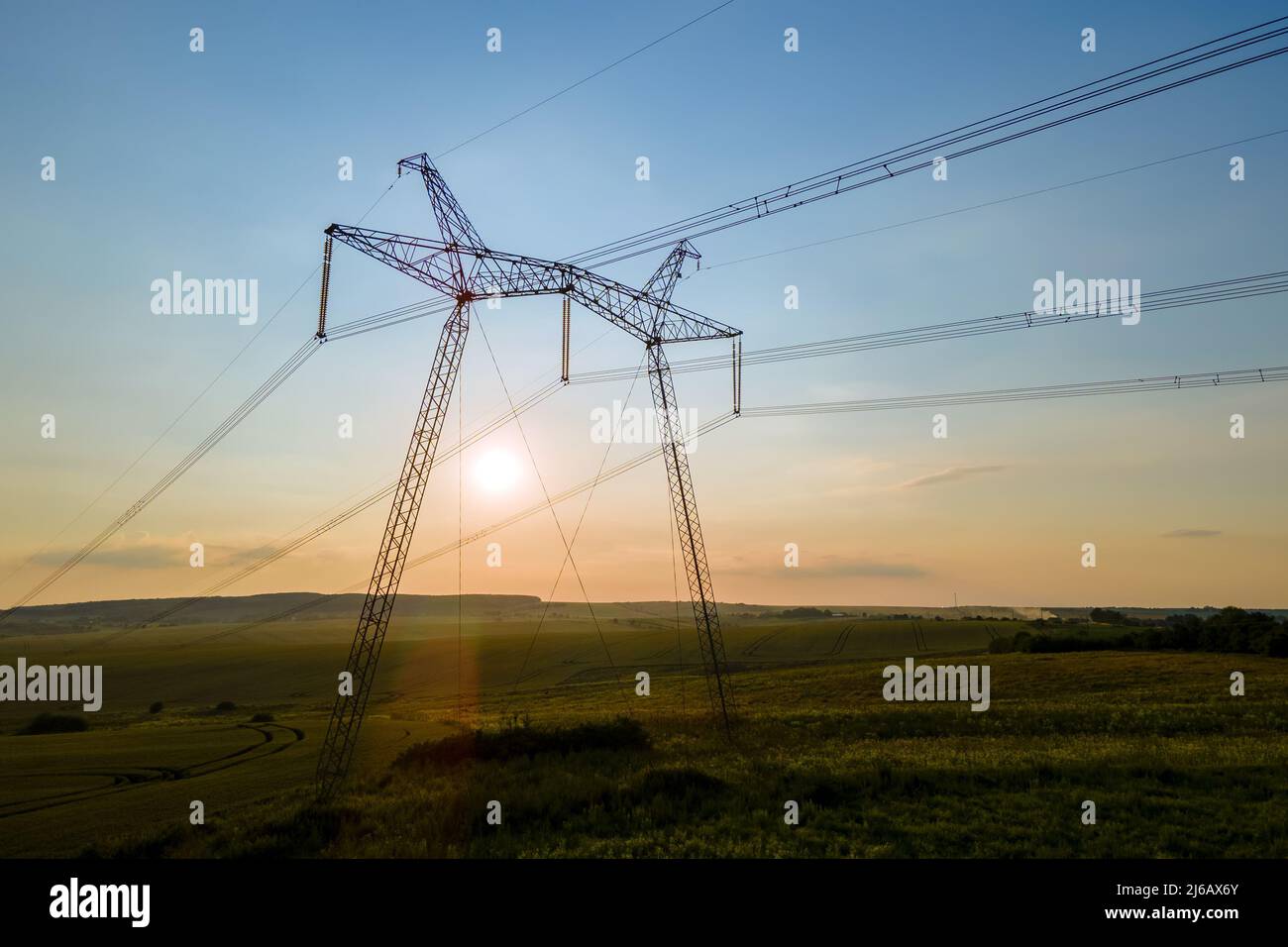 Dark silhouette of high voltage towers with electric power lines at ...