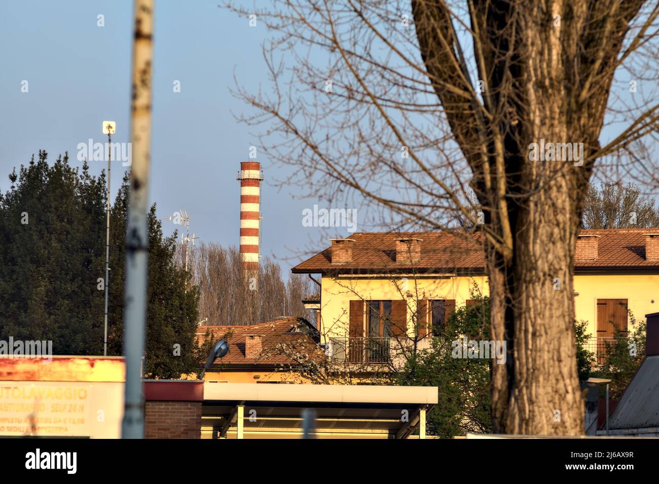 Residential area with a smokestack in the background at sunset Stock Photo