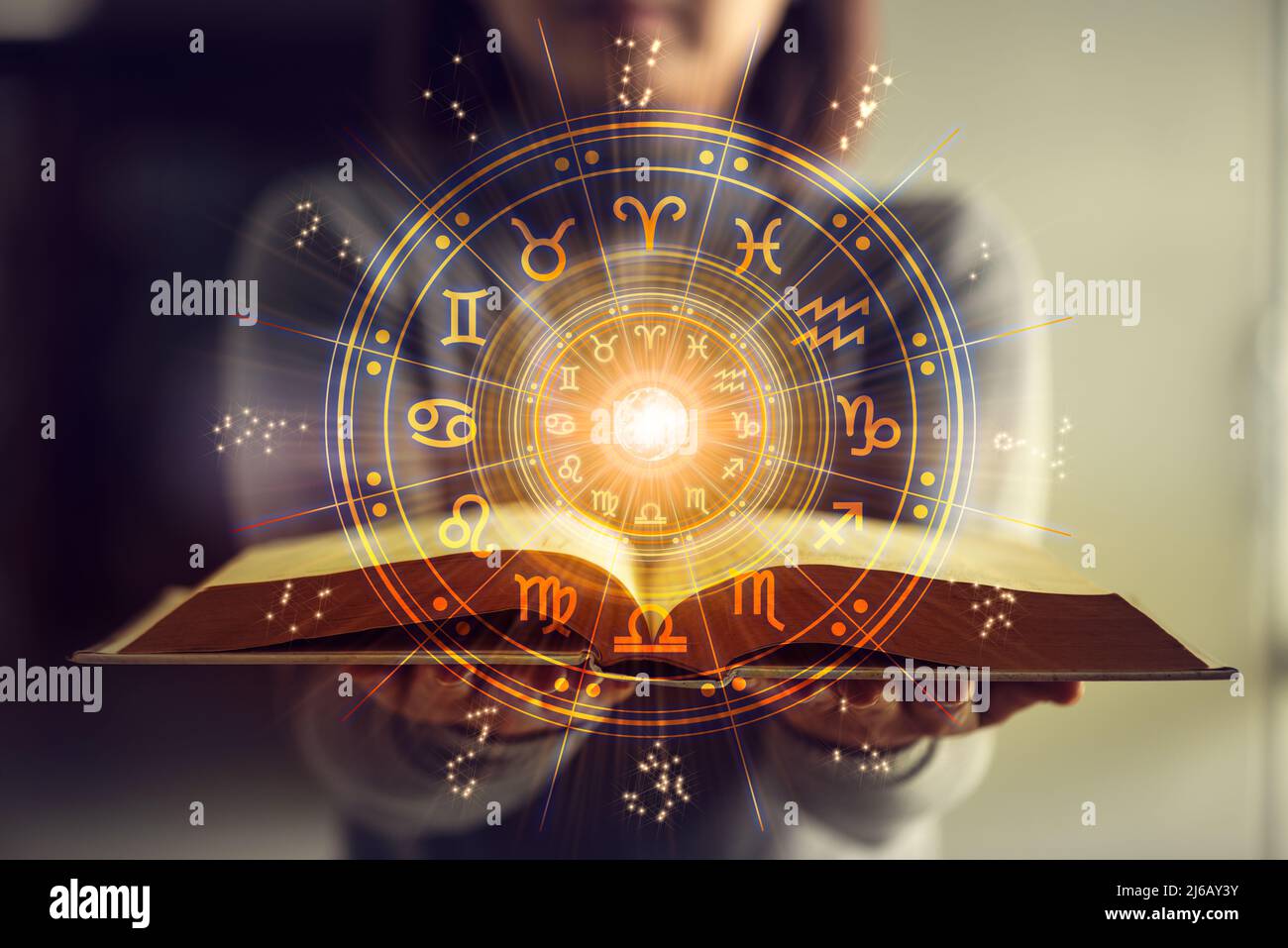 Woman holding a astrology book. Astrological wheel projection, choose a zodiac sign. Astrology esoteric concept. Stock Photo