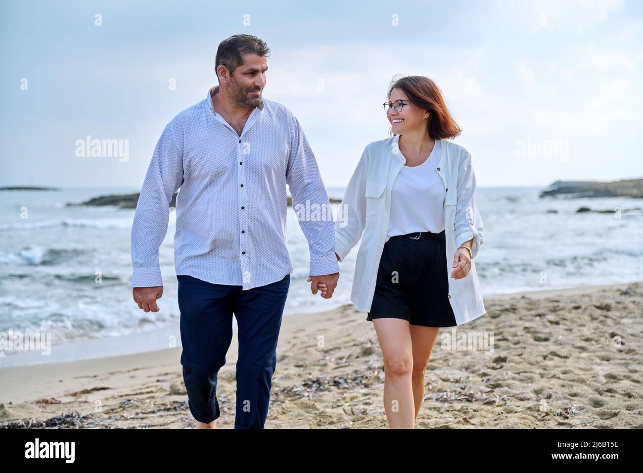 Happy middle-aged couple walking together on the beach. Stock Photo