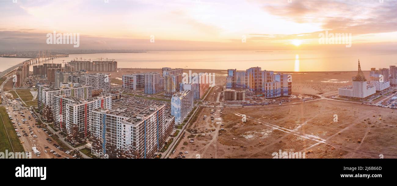 New residential buildings sea and sunset over it large panoramic aerial view. Drone point of view cityscape Stock Photo