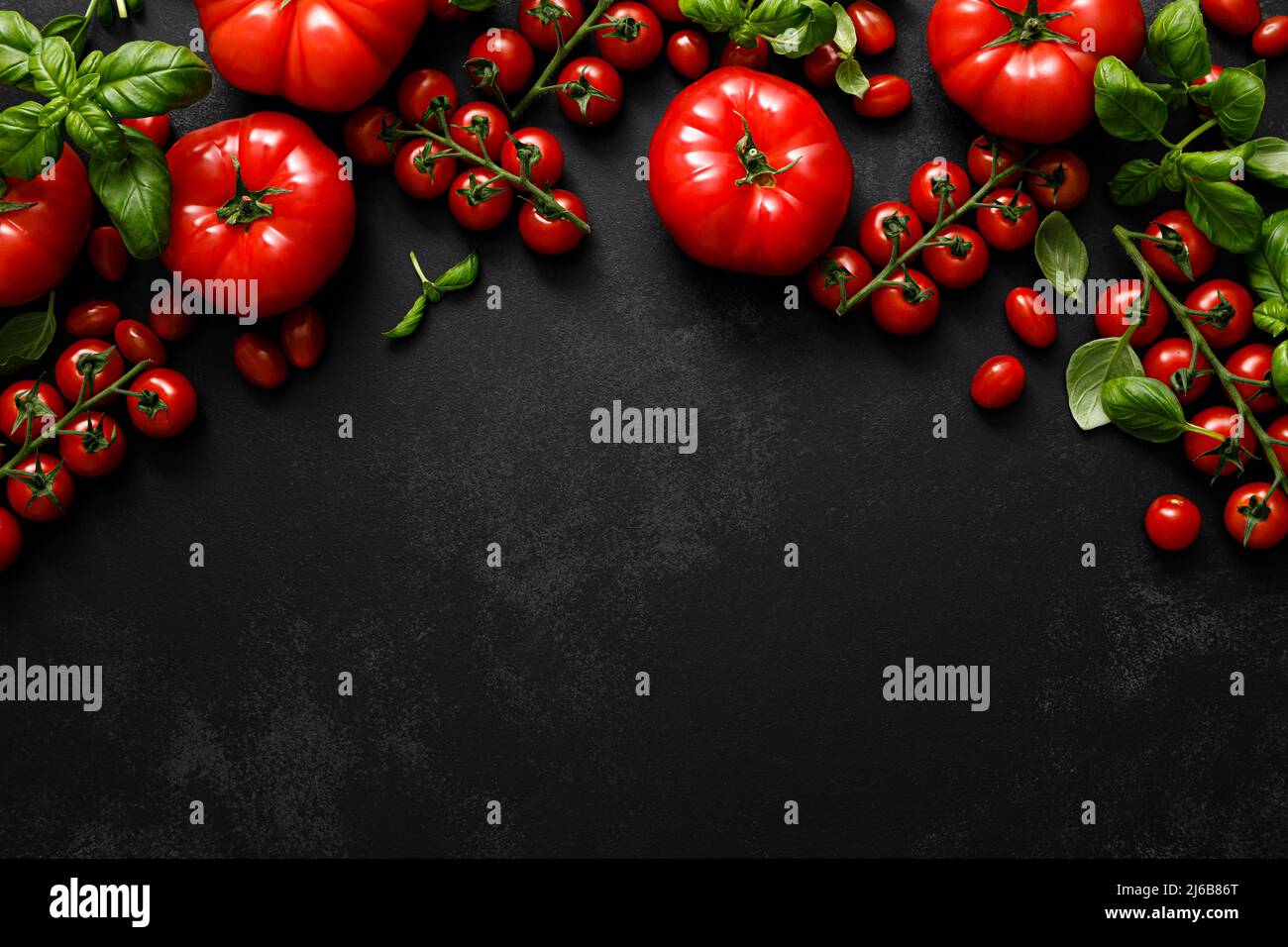 Tomatoes and basil on black background, top view, flat lay Stock Photo