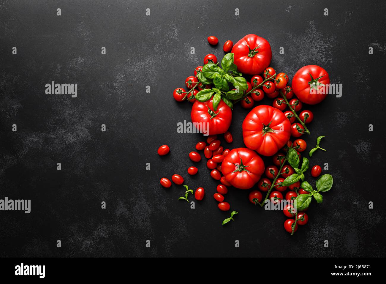 Tomatoes and basil on black background, top view, flat lay Stock Photo