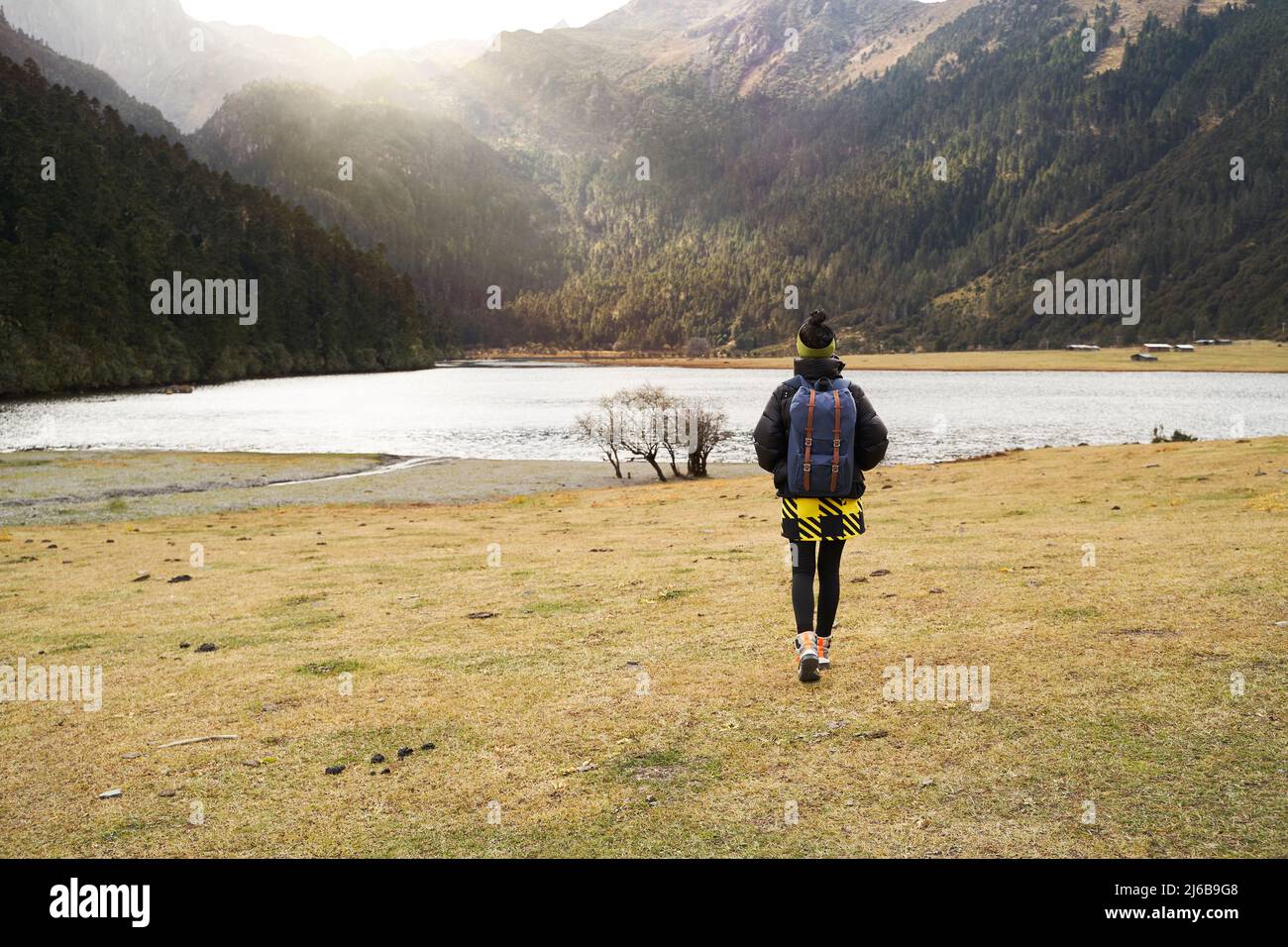 rear view of asian woman female tourist walking toward a lake at the foot of a mountain Stock Photo