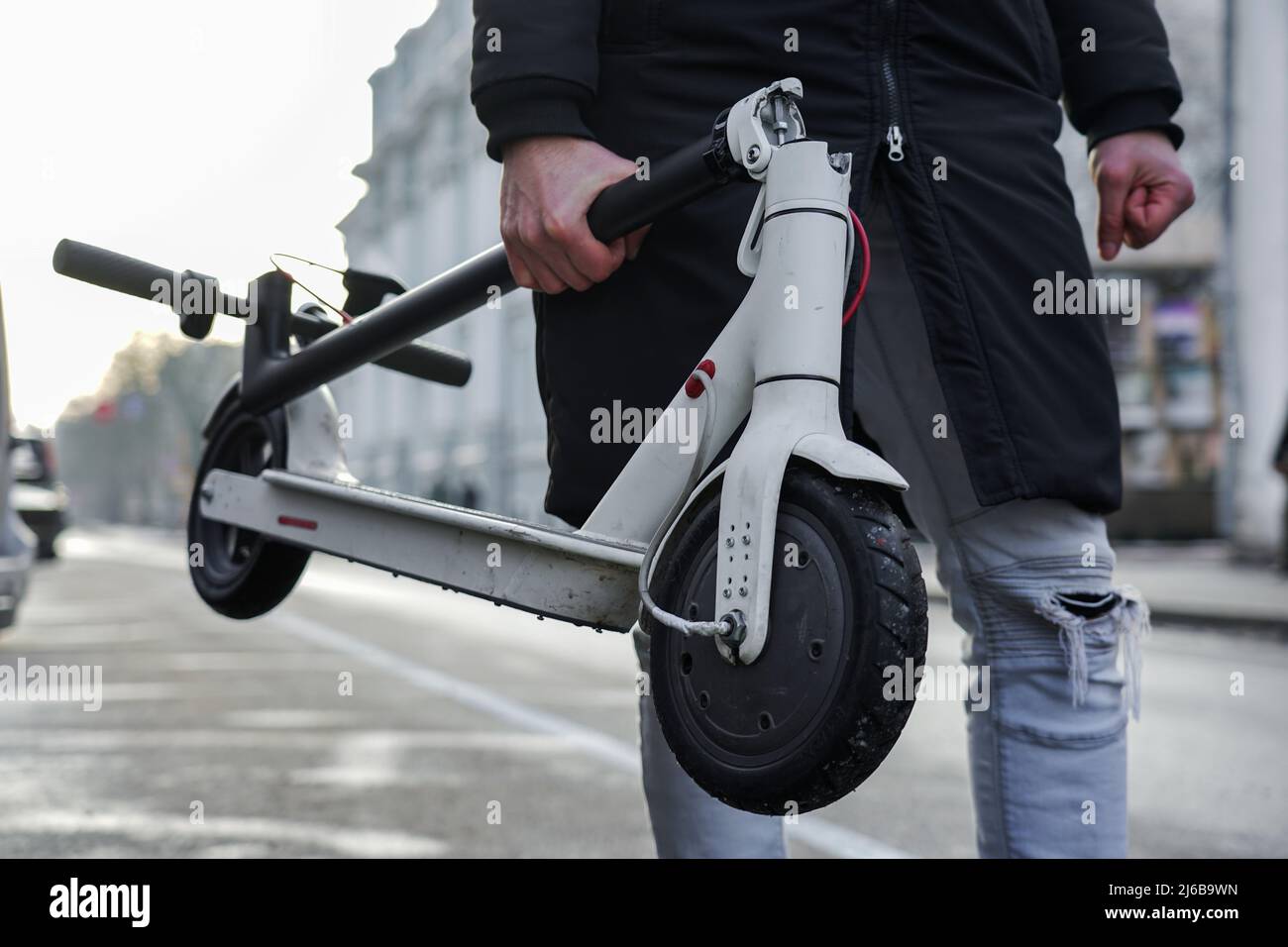 he guy is holding a folded electric scooter in his hand. Transportation