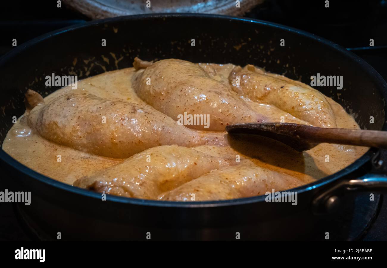 Red thai chicken curry simmering in a pan on a stove Stock Photo