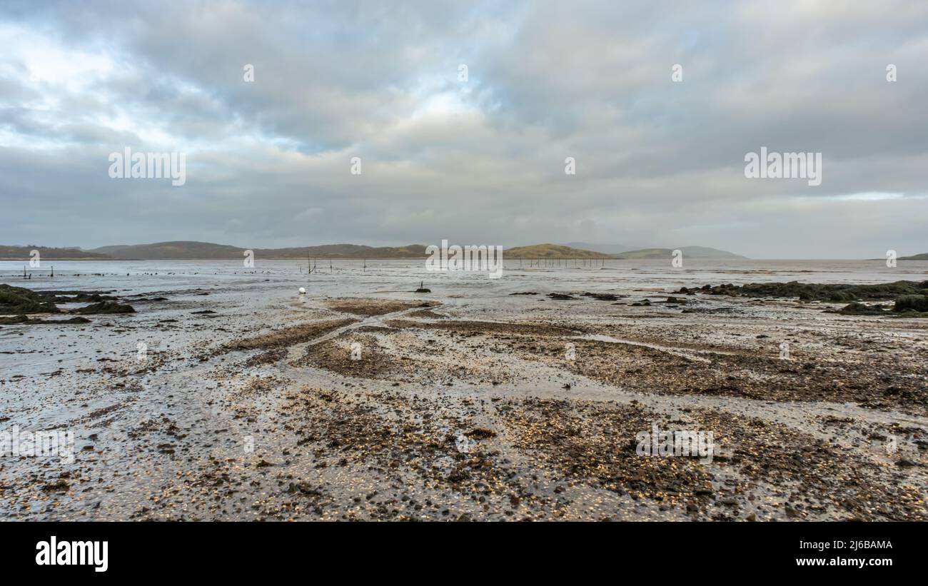 Stream flowing into Balcary Bay, with salmon fishing nets in the background, Auchencairn, Scotland Stock Photo