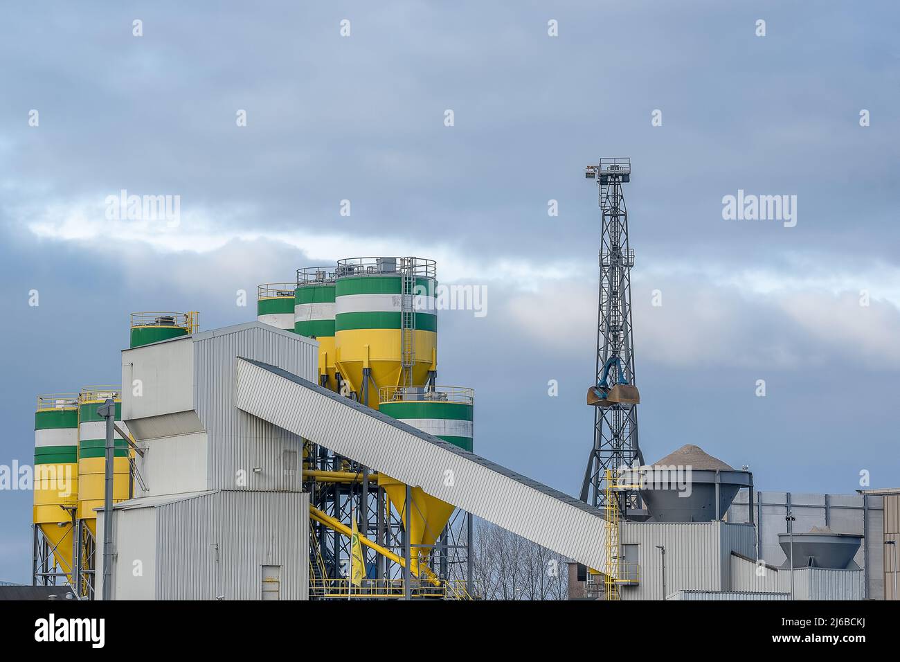 Cement factory with cranes for transporting raw materials. The silos in which the raw materials are mixed into cement and the conveyor belts are clear Stock Photo