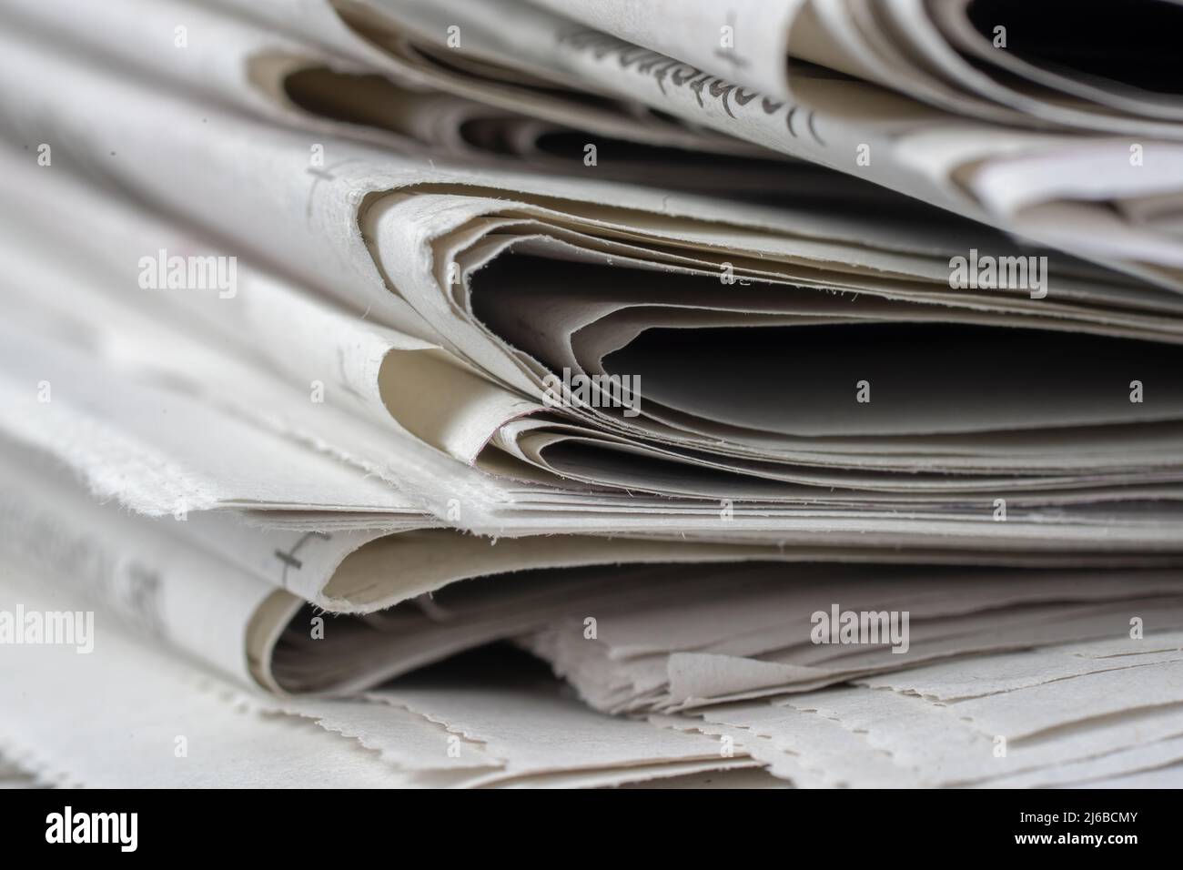 Macro shot of a stack of newspapers. The newspapers are folded and the articles are not legible Stock Photo