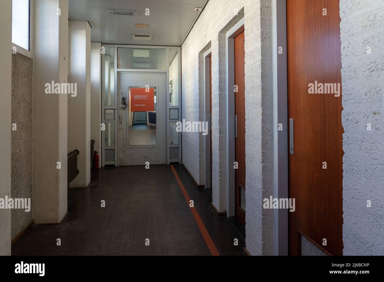 AMSTERDAM/NETHERLANDS-FEBRUARY 24: An empty corridor of a prison with tiles on the floor and open steel cell doors on which texts are scratched The ce Stock Photo