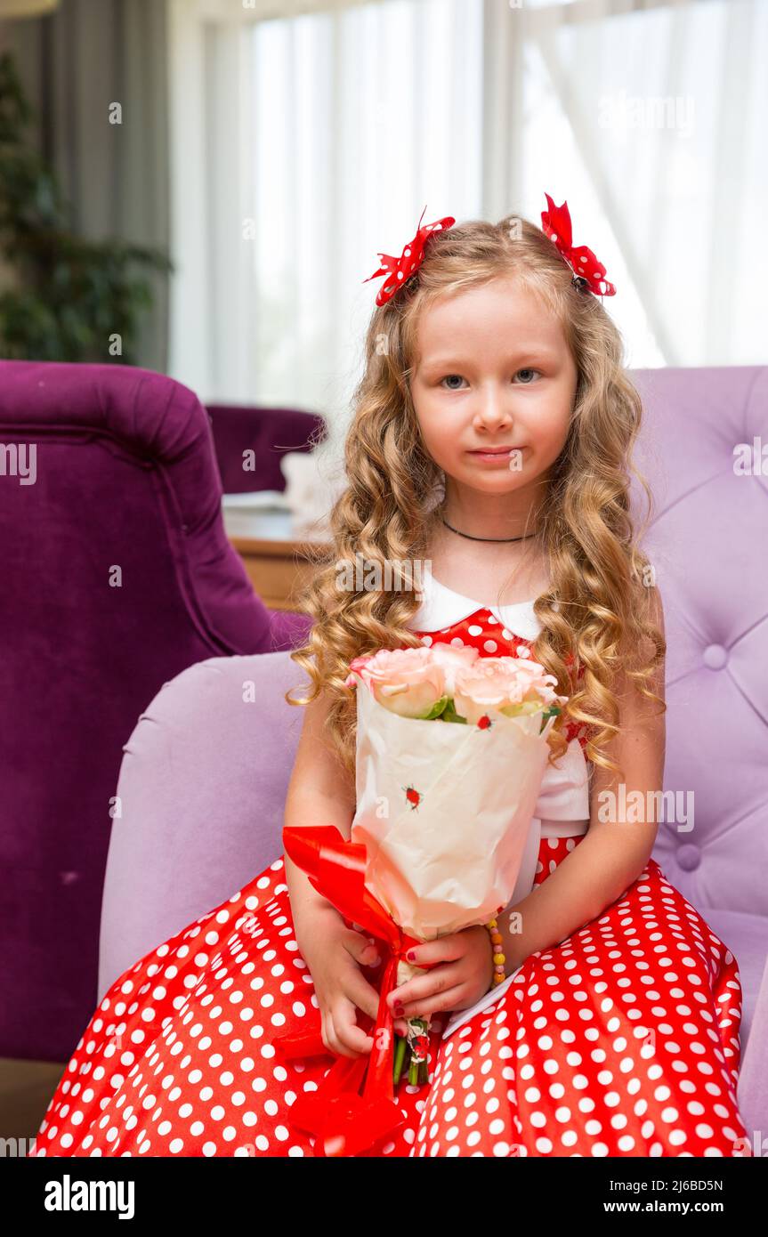 Happy kid girl celebrating birthday party with bouquet of flowers in cafe. Child name-day. Stock Photo